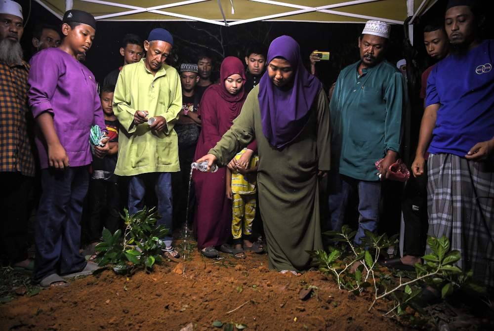 Nurain menyiram air mawar di atas kubur jenazah anaknya, Muhammad Akil di Tanah Perkuburan Islam Kampung Banggol Berangan di Baling pada Jumaat. Foto Bernama