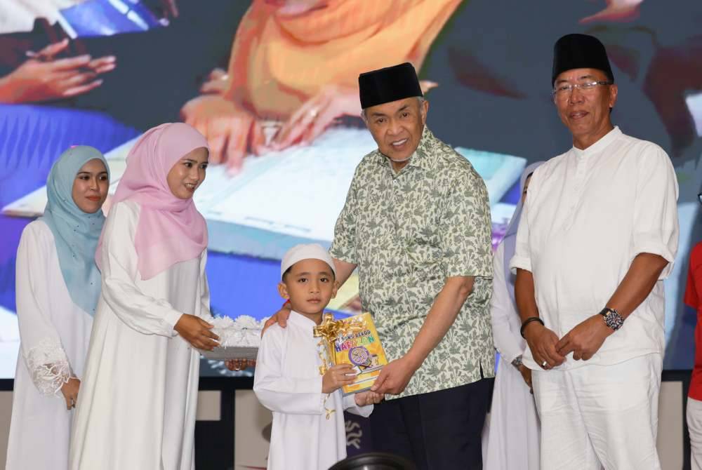 Ahmad Zahid (dua, kanan) menyerahkan modul Pra Tahfiz Kemas kepada pelajar Tabika Kemas Kampung Seberang Jertih 2, Besut, Luqman Haqqim Abdul Haqqim, 6, pada Majlis Pelancaran Pra Tahfiz Peringkat Kemas Terengganu pada Sabtu. Foto Bernama