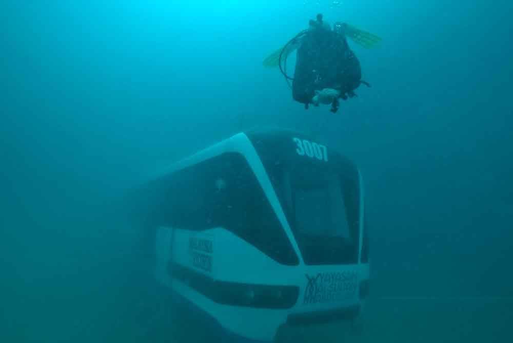 Seorang penyelam bersama gerabak LRT yang diturunkan di dasar laut Tioman. Foto Prasarana