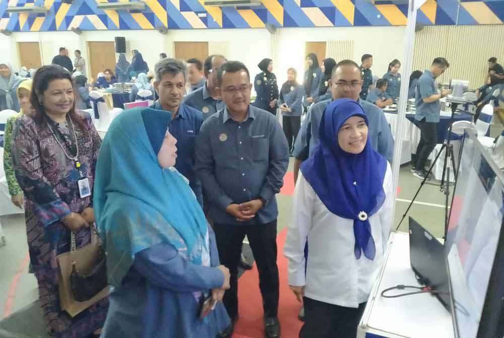 Fazidah (kanan) melihat demonstrasi penggunaan sistem DDMS selepas menyempurnakan Majlis Pelancaran DDMS 2.0 MDBG di Dewan Bandaran Kinta di sini pada Rabu.