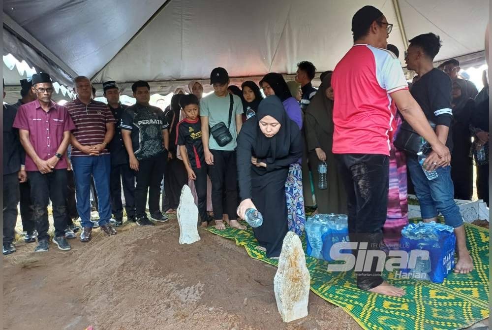 Salah seorang ahli keluarga Nur Farah Kartini menyiram air selepas bacaan talkin berakhir di Tanah Perkuburan Islam Kampung Nyiur Manis, di sini pada Khamis. Foto Sinar Harian-NORAWAZNI YUSOF