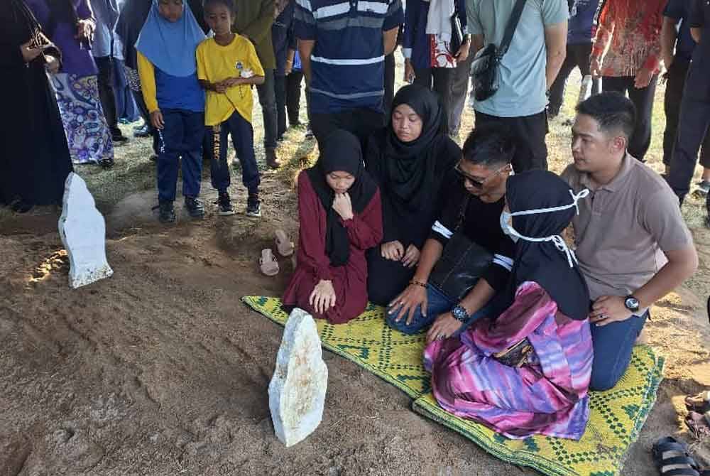 Mohd Farriza Amir (depan, dua dari kanan) bersama ibu serta ahli keluarga menahan sebak selepas selesai urusan pengebumian jenazah Nur Farah Kartini di Tanah Perkuburan Islam Kampung Nyiur Manis di sini, pada Khamis.