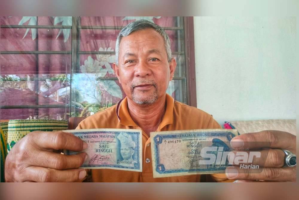 Abdul Rashid menunjukkan not RM1 dan not nilai Sama Brunei yang disimpan sejak lebih 30 tahun lalu.