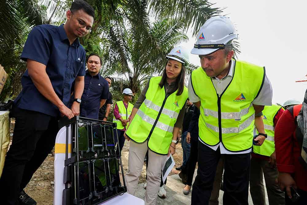 Nie Ching (dua, kanan) bersama Jafni (kanan) melihat ujian kelajuan internet pada Lawatan Kerja Menara Telekomunikasi di bawah Projek Jendela Fasa Satu di Kampung Murni Jaya 2 pada Jumaat. Foto Bernama