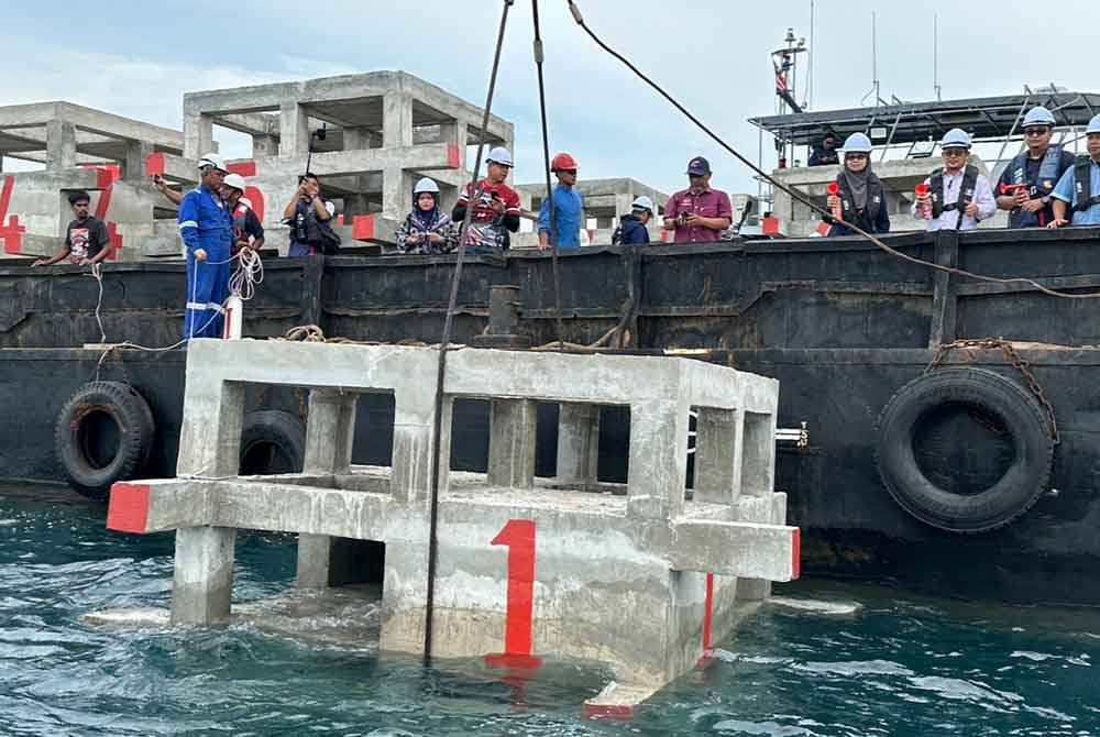 Erniyta (empat dari kanan) mengiringi Tuan Mohd Saripudin (tiga dari kanan) yang menyaksikan tukun dilabuhkan di Tok Bali pada Ahad.