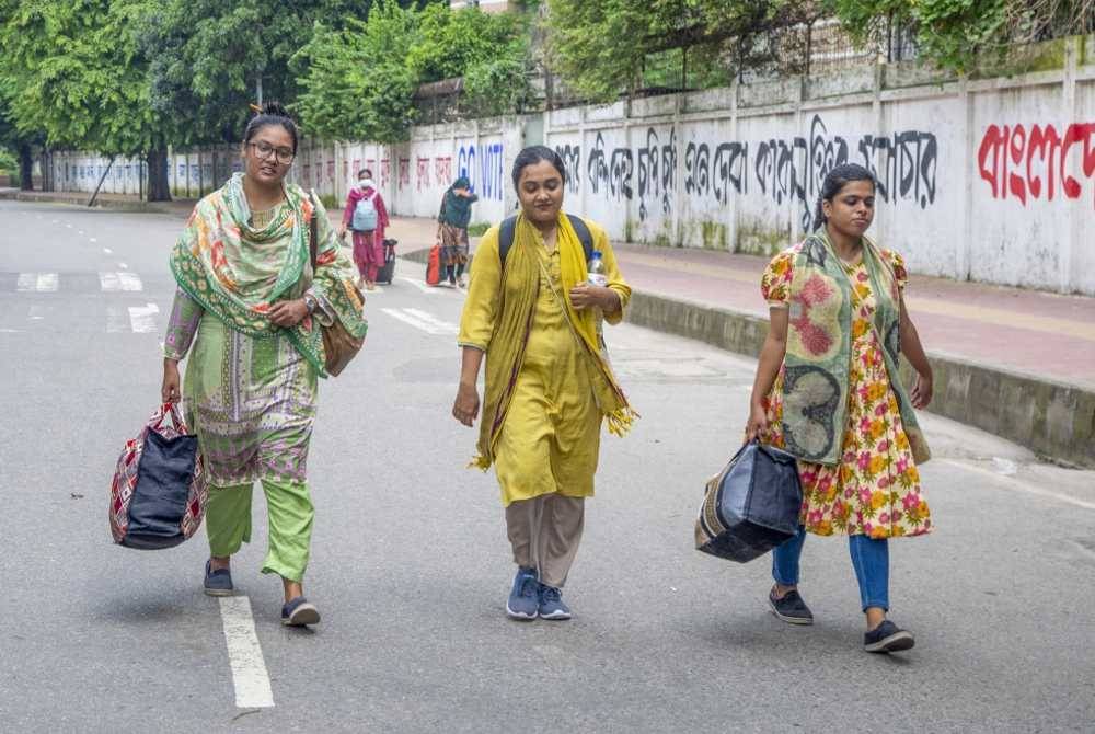 Pelajar berjalan membawa bagasi mereka ketika meninggalkan kampus universiti di Dhaka, susulan penutupan institusi itu akibat protes berterusan. Foto EPA