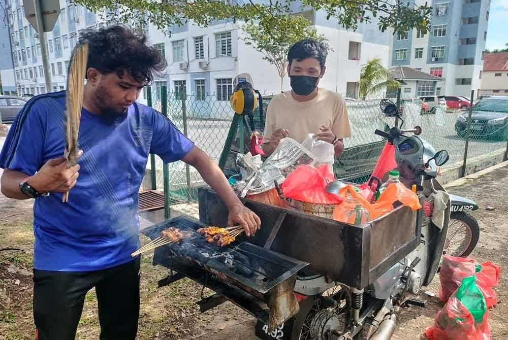 Muhammad Ashraf (dua, kiri) bersama sepupunya Abu Zanib zainudin,34, membakar sate yang ditempah pelanggan.