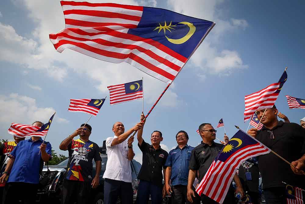 Exco Sains, Teknologi, Inovasi dan Komunikasi Digital negeri Datuk Fairul Nizam Roslan (tiga, kiri) mengibarkan Jalur Gemilang selepas menerimanya dari konvoi Kembara Merdeka Jalur Gemilang (KMJG) Negeri Sembilan pada majlis Perasmian KMJG 2024 Melaka di Freeport A&#039;Famosa Outlet, hari ini.