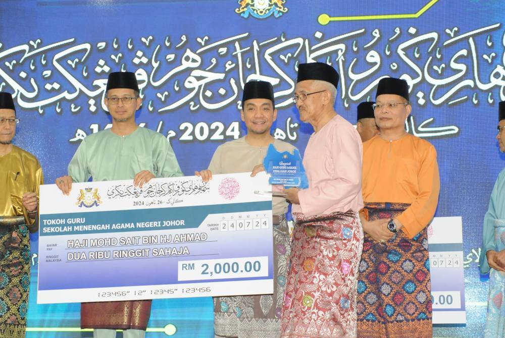 Mohd Sait (kanan) menerima anugerah Tokoh Guru daripada Onn Hafiz (tengah) pada Majlis Sambutan Hari Guru Agama Kerajaan Negeri Johor di Savanna Hill Resort, Ulu Tiram, Johor Bahru, pada Rabu.