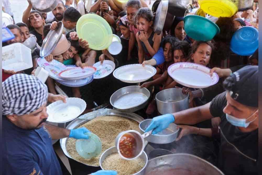 Penduduk Palestin menunggu giliran bagi menandapatkan makanan di pusat pengedaran bantuan yang dibina oleh seorang lelaki muda dari keluarga Madhoun di Beith Lahia. Foto AFP