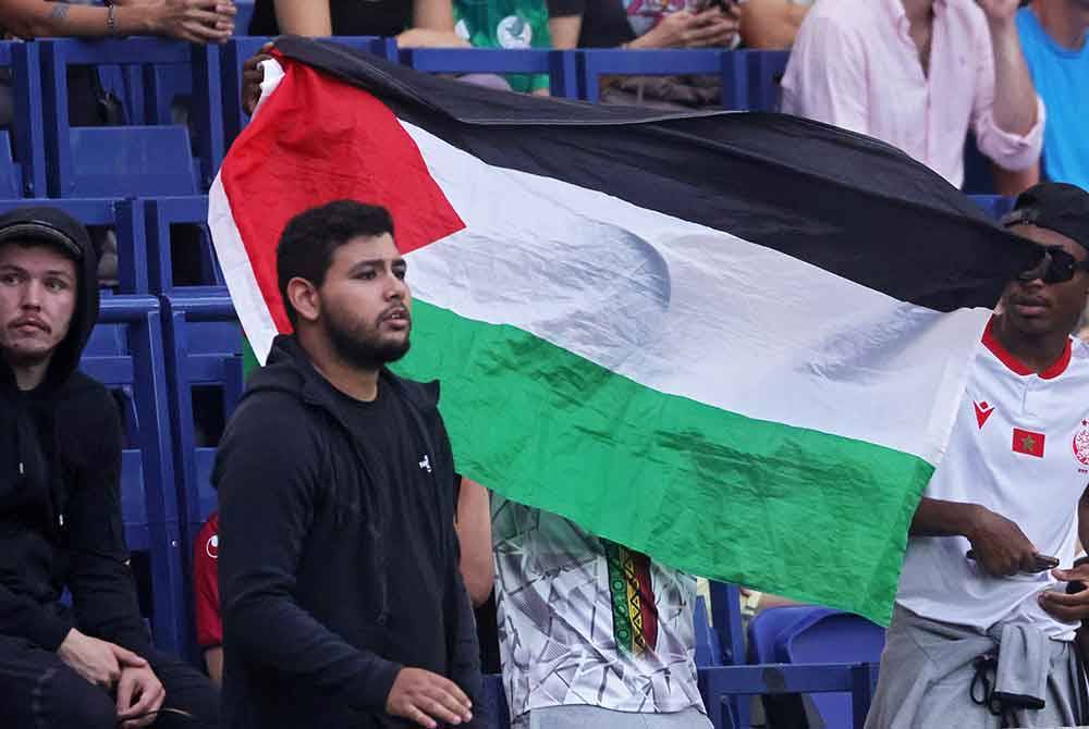 Penyokong Mali memegang bendera Palestin semasa aksi pembukaan bola sepak Olimpik antara Mali dan Israel. Foto EPA