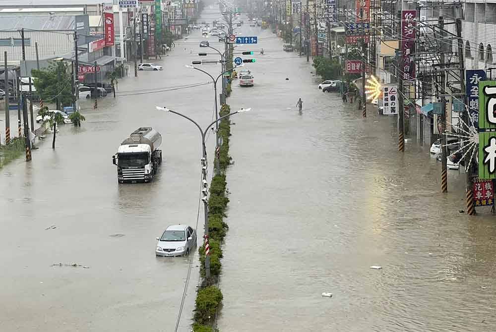 Kenderaan terpaksa meredah banjir di Kaohsiung yang disebabkan Taufan Gaemi. - AFP