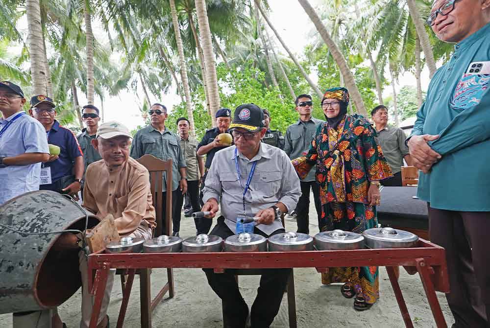 Saifuddin Nasution (tengah) cuba bermain alat muzik kulintangan ketika tinjauan keselamatan Kementerian Dalam Negeri ke Zon Selamat Timur Sabah bersama perwakilan asing di Pulau Mabul pada Jumaat. Foto Bernama