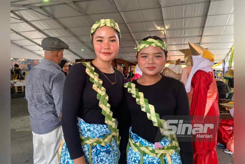 Shamira (kiri) bersama Angelia menggayakan anyaman tempok masyarakat Orang Asli ketika hadir ke Karnival Rakyat Karangkraf di sini pada Sabtu.