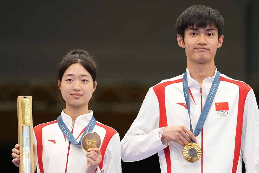 Huang Yuting dan Sheng Lihao di podium selepas memenangi emas acara 10m air rifle berpasukan campuran Paris 2024 di Pusat Menembak Kebangsaan Perancis, Chateauroux. Foto: AFP