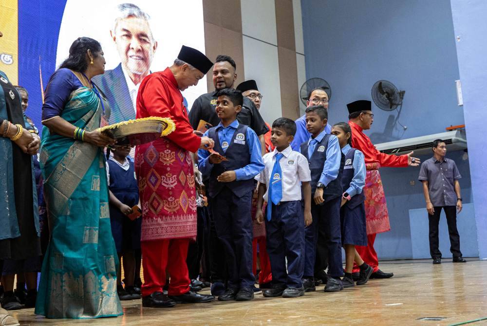 Ahmad Zahid menyampaikan sumbangan kepada murid-murid pada Majlis Penyampaian Sumbangan Bantuan Persekolahan SJK (T) Parlimen Bagan Datuk di Dewan Dato Mohamed Jamrah hari ini. Foto Bernama