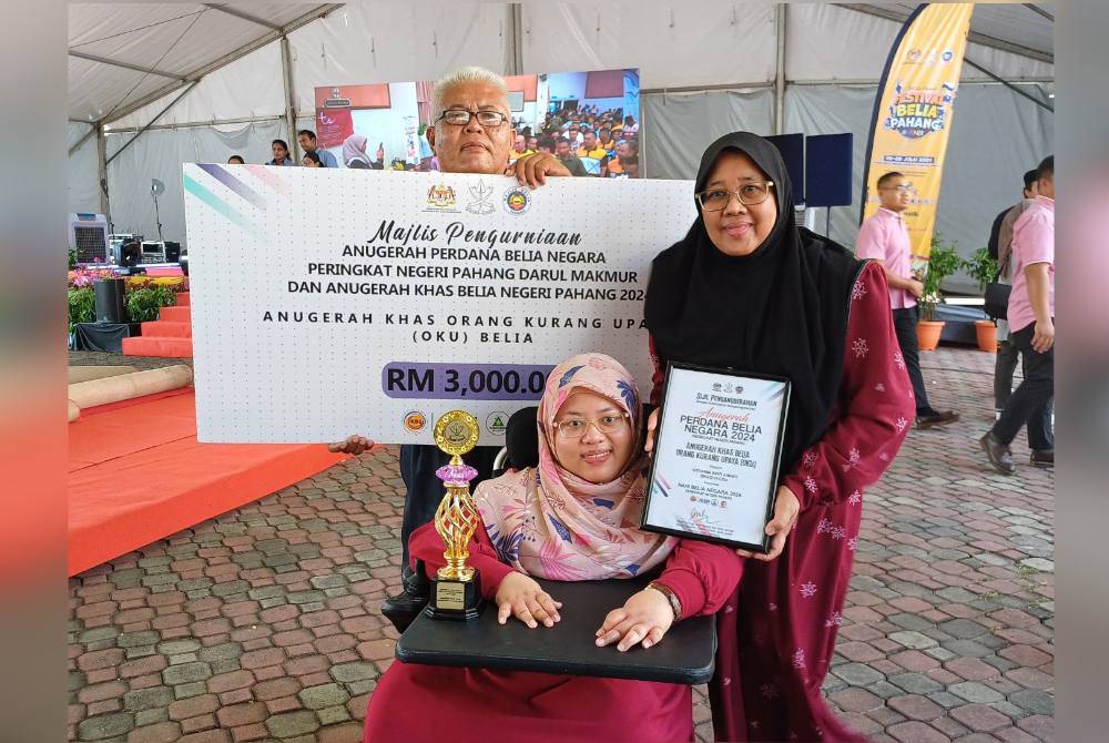 Siti Hawa (tengah) bersama ibu dan ayahnya merakam gambar kenangan selepas menerima anugerah khas Belia OKU.