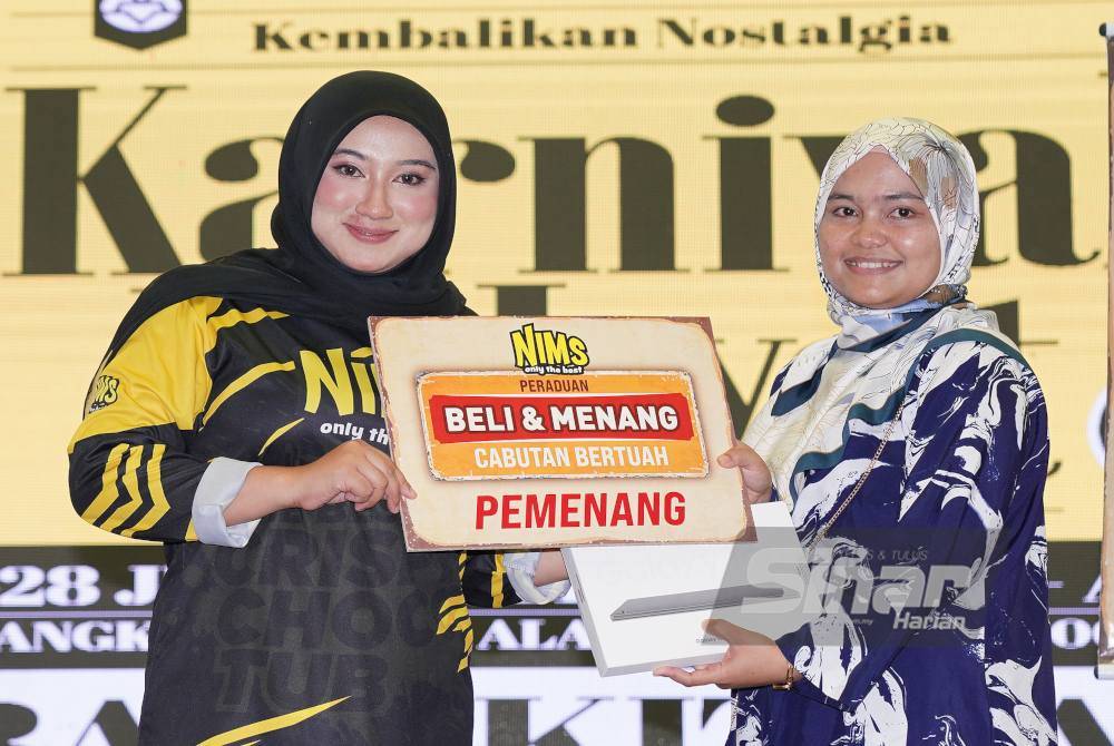 Tengku Norhanim (kiri) menyampaikan hadiah cabutan bertuah kepada pengunjung yang membuat pembelian produk Nims di Karnival Rakyat Karangkraf pada Ahad.