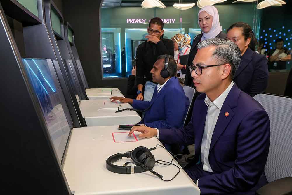 Fahmi (kanan) mencuba komputer simulasi ‘Moderation Workstation TikTok’ ketika sesi lawatan ke Transparency and Accountability Center (TAC) TikTok, pada Isnin. Foto Bernama