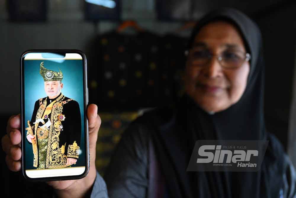 Kak Nah menunjukkan gambar Yang di-Pertuan Agong memakai hasil pelengkap busana dihasilkannya.