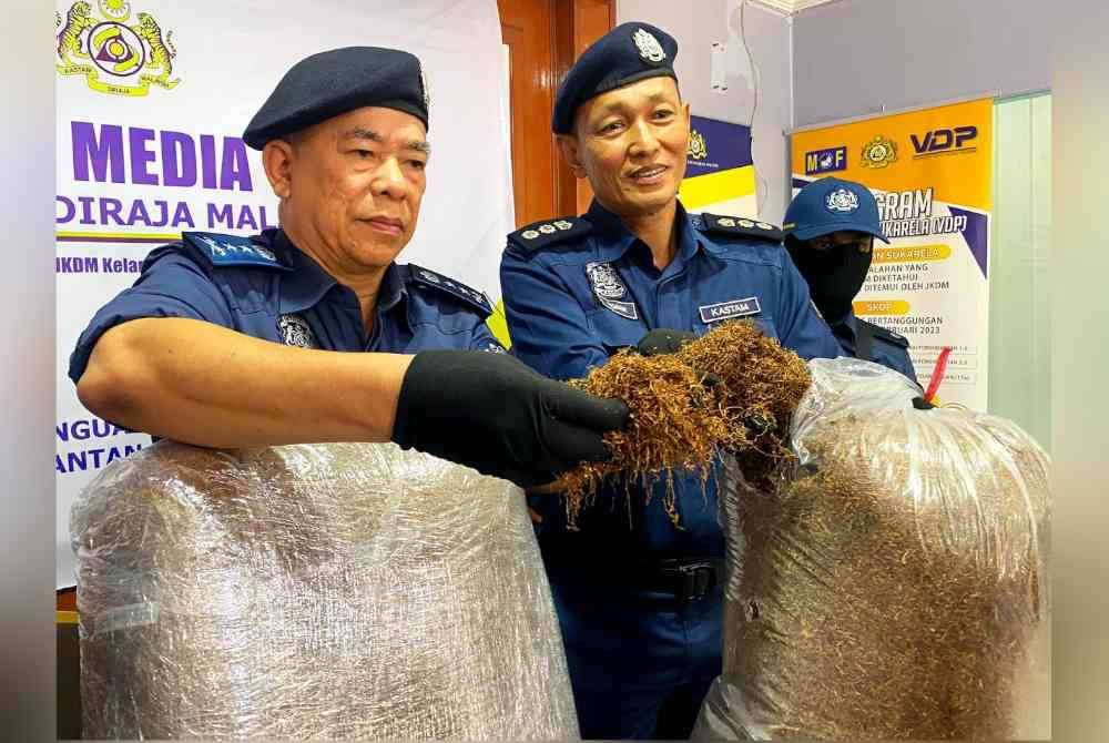 Wan Jamal Abdul Salam (kiri) menunjukkan sebahagian daripada tembakau kering yang berjaya dirampas.