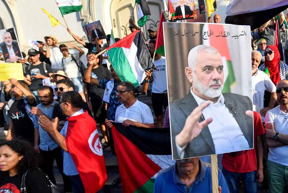 Rakyat Tunisia mengibarkan bendera Palestin dan memegang potret Ismail Haniyeh semasa protes di ibu negara Tunisia bagi mengecam pembunuhannya. Foto AFP