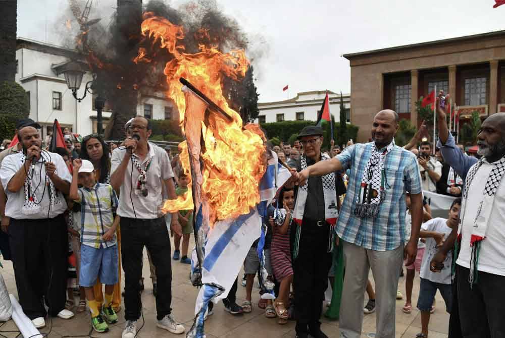 Orang ramai membakar bendera Israel semasa protes mengecam pembunuhan pemimpin Hamas, Ismail Haniyeh di Rabat pada 31 Julai 2024. Foto AFP