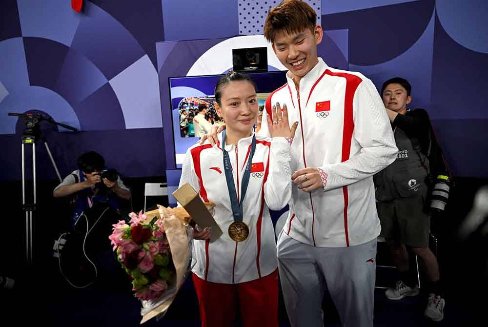 Ya Qiong (kiri) menunjukkan cincin lamaran oleh Liu Yuchen selepas acara penyampaian pingat untuk aksi beregu campuran di Sukan Olimpik Paris. Foto AFP