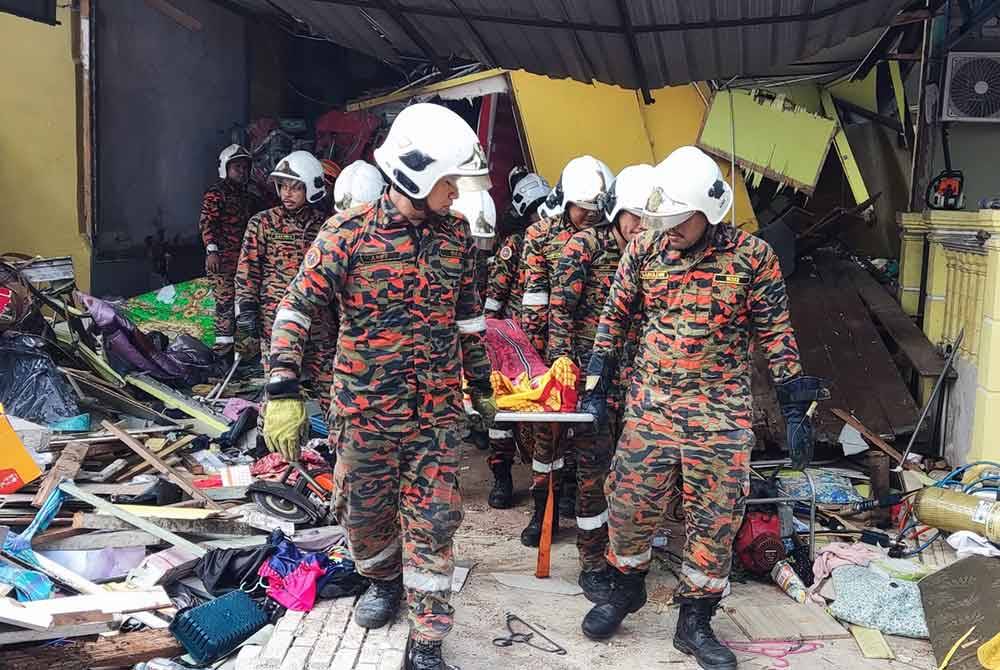 Anggota bomba mengeluarkan mayat mangsa dari runtuhan rumah pada Sabtu. Foto JBPM