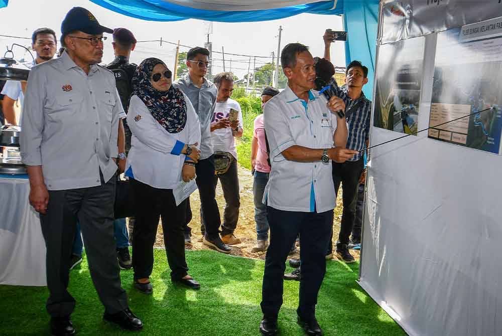 Anwar (kiri) mendengar penerangan daripada Ahmad Anuar (kanan) ketika meninjau kemajuan tapak projek pembinaan PLSB Sungai Kelantan Fasa 1 di Tunjung pada Sabtu. Foto Bernama