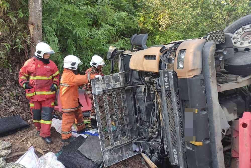 Anggota bomba berusaha mengeluarkan mangsa yang tersepit dalam kejadian lori terbabas di Kampung Laloh, Kuala Krai pada Sabtu.