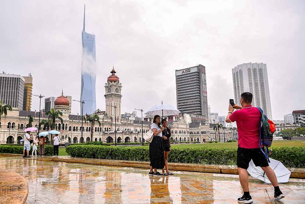 Para pelancong yang mengunjungi Dataran Merdeka menggunakan payung ketika tinjauan foto Bernama di sekitar ibu kota hari ini.