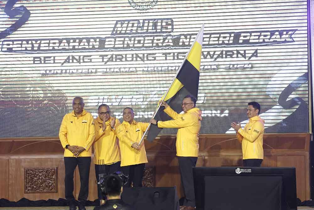 Saarani (tengah) menyerahkan bendera Perak kepada Ahmad Suaidi sempena Majlis Penyerahan Bendera Negeri Perak Belang Tarung Tiga Warna Kontinjen Sukma Negeri Perak 2024 di Dewan Bankuet Bangunan Perak Darul Ridzuan pada Ahad.