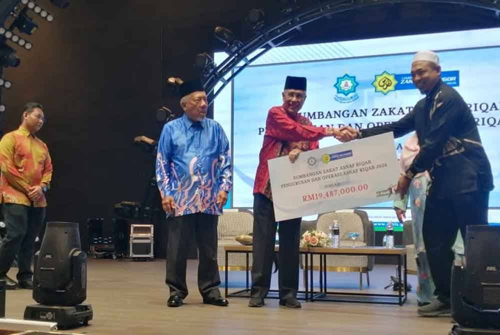 Abdul Aziz (dua kanan) menyerahkan replika cek peruntukan zakat asnaf riqab kepada wakil pengusaha rumah ar-Riqab Selangor.