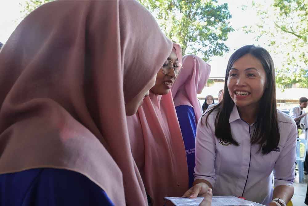 Nie Ching (kanan) menyampaikan kelengkapan alat tulis kepada pelajar pada Majlis Cemerlang Hari Ini, Gemilang Esok di Sekolah Menengah Kebangsaan Tunku Abdul Rahman Putra hari ini. - Foto: Bernama