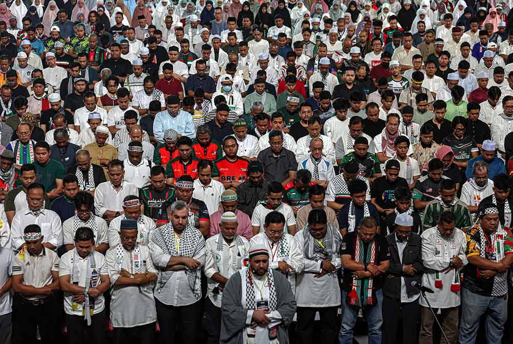 Peserta perhimpunan menunaikan solat Maghrib secara berjemaah dan diketuai imam dari negara Palestin pada Himpunan Pembebasan Palestin di Axiata Arena. Foto Bernama