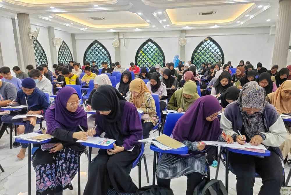 Afifah (kiri) maisarah (tengah) dan insyirah (kanan) ketika mengikuti kelas tuisyen percuma di Surau Al Redhuan Taman Semabok Perdana, di sini, pada Ahad.