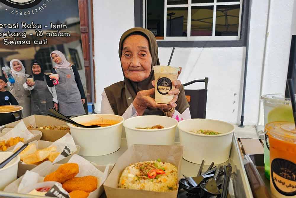 Opah Yang menunjukkan makanan dan minuman yang dijual di kafenya terletak di Kampung Empai, Kampung Gajah.