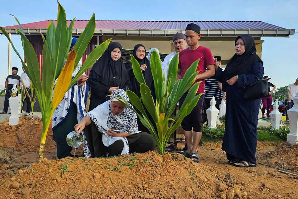 Ahli keluarga menyiram air di pusara Allahyarham Muhammad Firdaus selepas selamat dikebumikan di Tanah Perkuburan Islam Parit Jay, Matang Jelutong, Bagan Serai pada Isnin.