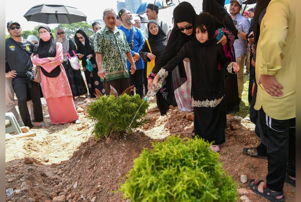 Camelia menyiram pusara bapanya. Foto Bernama