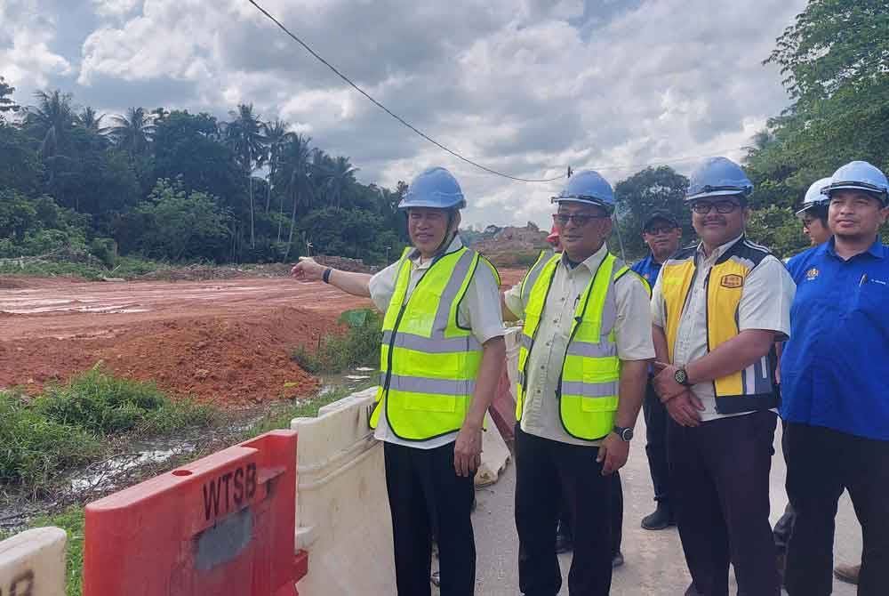 Ahmad (kiri) menunjukkan tahap perkembangan projek pembinaan jalan baharu di Bertam Lama, Gua Musang pada Isnin.