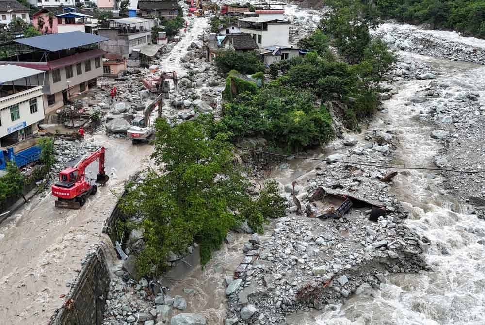 Gambar dron udara yang menunjukkan pasukan penyelamat mengendalikan jengkaut untuk memulihkan trafik di Lebuhraya Nasional 318 di Kampung Ridi, Bandar Kangding, Wilayah Autonomi Tibet Garze, Wilayah Sichuan di barat daya China. - Foto: Xinhua