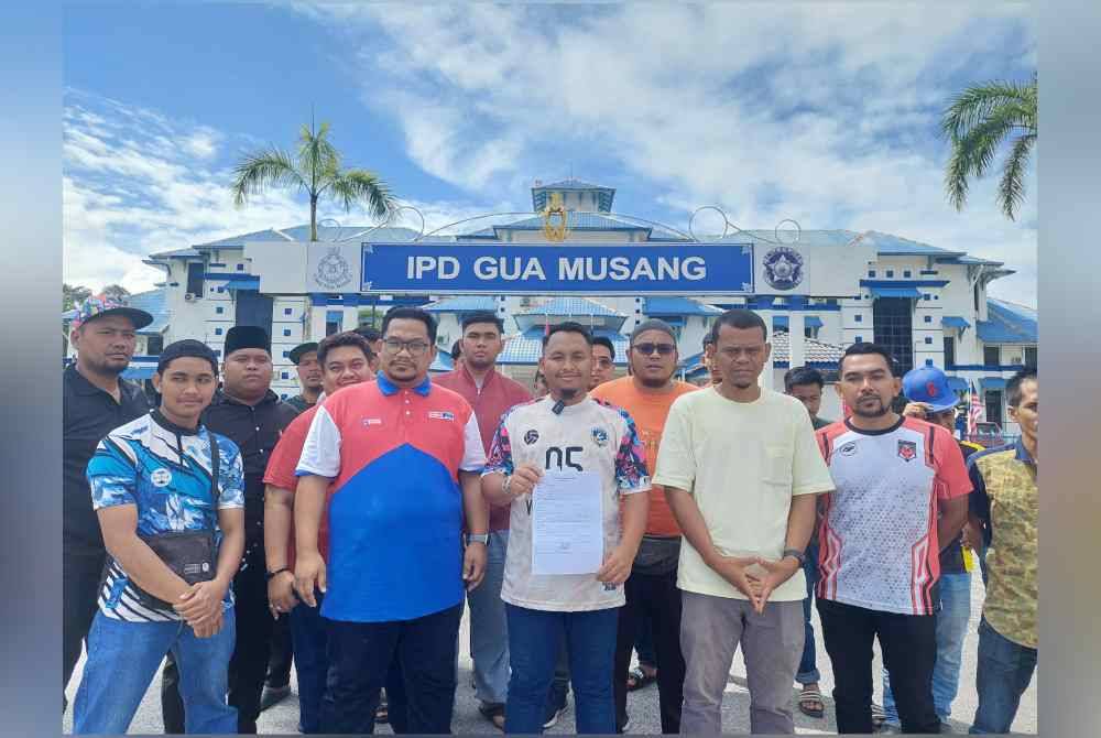 Muhammad Zaidi (depan, tiga kiri) bersama ahli Pemuda UMNO Gua Musang menunjukkan salinan laporan polis yang dibuat di IPD Gua Musang pada Selasa.