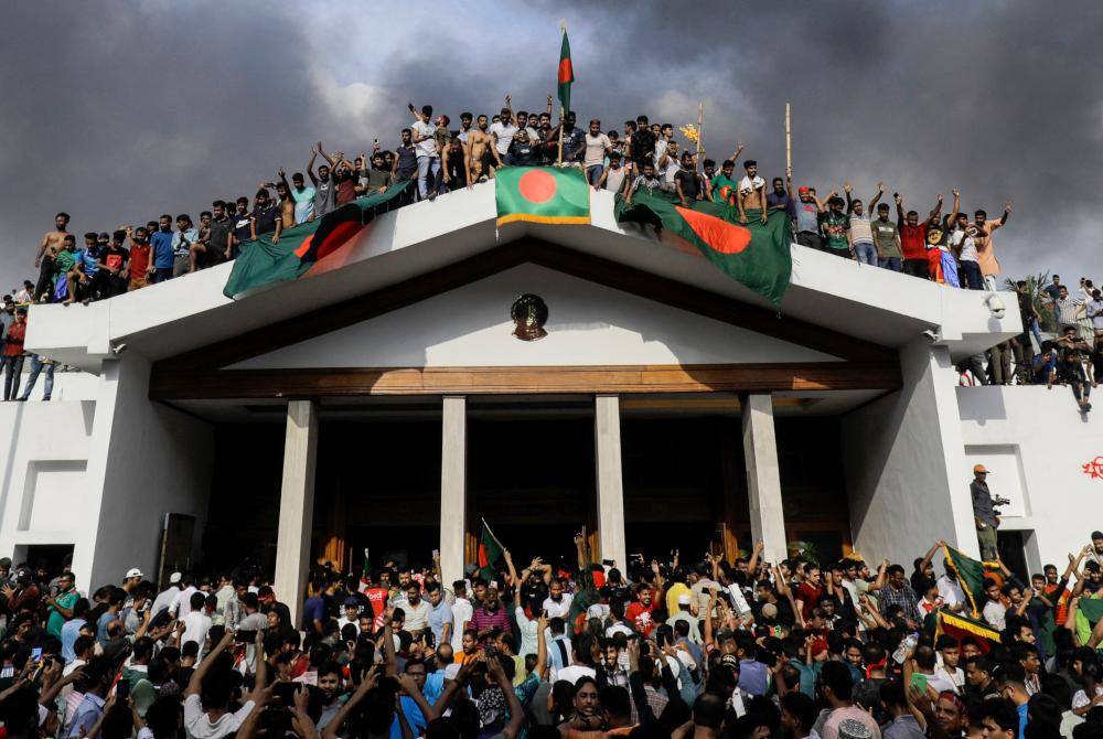 Penunjuk perasaan mengibarkan bendera kebangsaan ketika menyerbu kediaman rasmi Perdana Menteri di Dhaka.