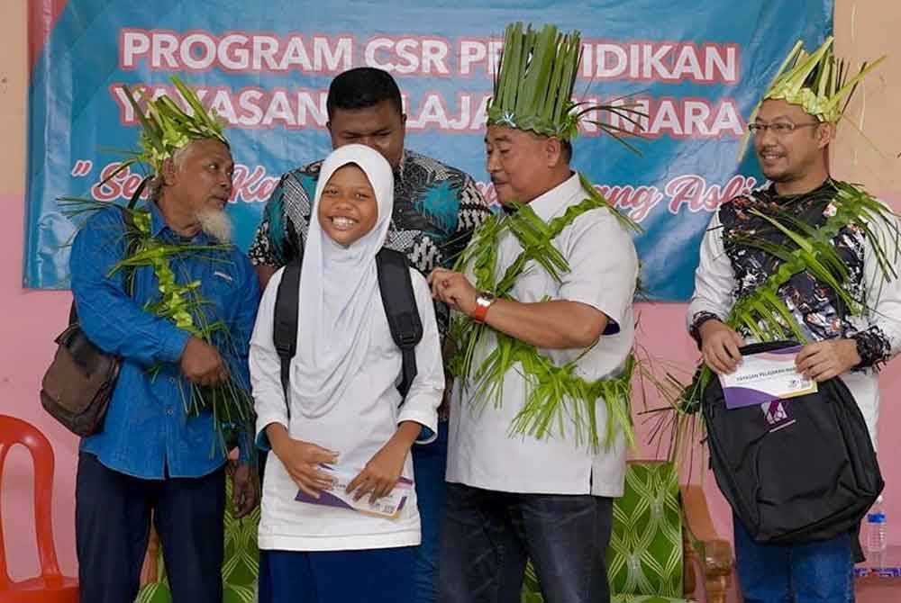 Ismail menyampaikan bantuan kelengkapan sekolah kepada murid Orang Asli pada program CSR YPM di Gua Musang.