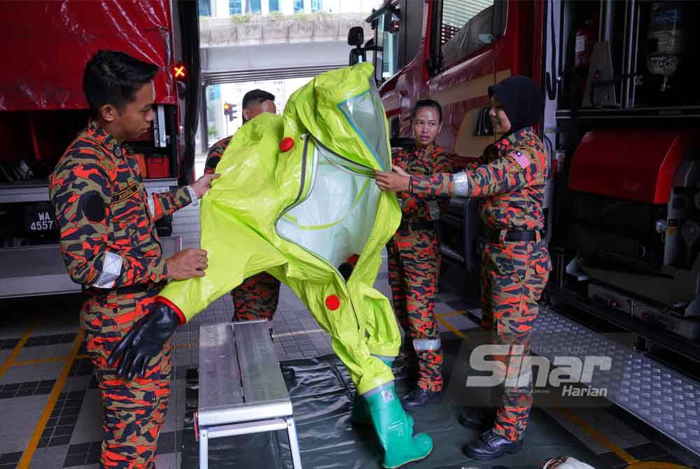 Haryati (kanan) dan Hui Naa (dua dari kanan) menunjukkan sut yang digunakan oleh anggota terlibat dalam pasukan Hazmat.