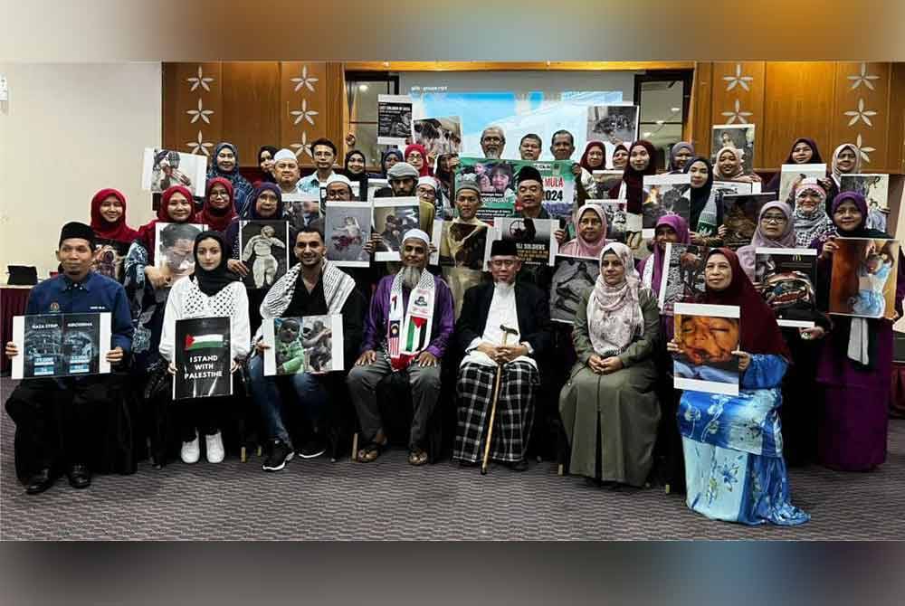 Suad (duduk, dua dari kanan) bersama Presiden Mapim, Mohd Azmi Abdul Hamid (tiga dari kanan) ketika melancarkan program bantuan tunai keluarga Gaza baru-baru ini.