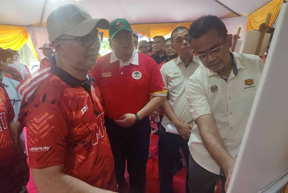 Tengku Zafrul (kiri) melihat pelan perancangan pembinaan Dewan Serbaguna Terbuka Kampung Tebuk Mufrad pada Sabtu.