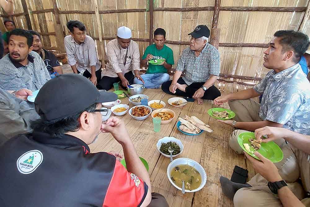 Mohd Rizwadi (lima dari kiri) bersama pimpinan PN menikmati hidangan tradisional Orang Asli ketika berkunjung ke Kampung Langsat, Kuala Betis, Gua Musang pada Sabtu.