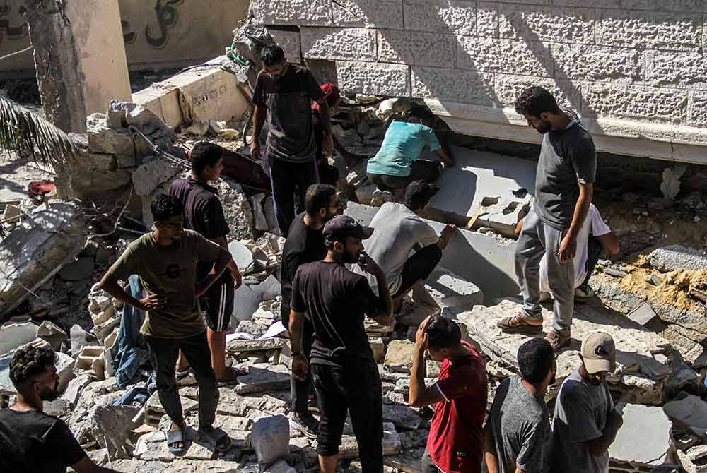 Orang ramai mencari mangsa di sekolah yang rosak akibat serangan udara Israel di Bandar Gaza. Foto Xinhua